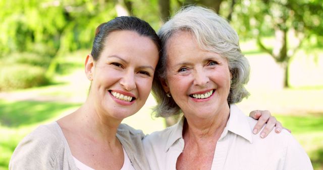 Mother and adult daughter smiling at camera in the park on a sunny day - Download Free Stock Photos Pikwizard.com