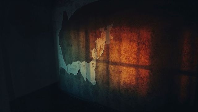 Textured wall with peeling wallpaper and sunlight in rustic room