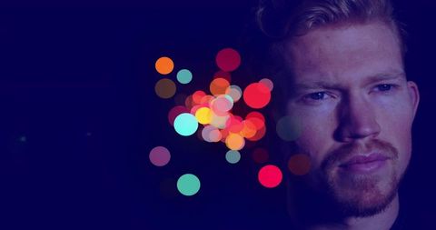 Introspective Man with Colorful Bokeh in Studio Setting