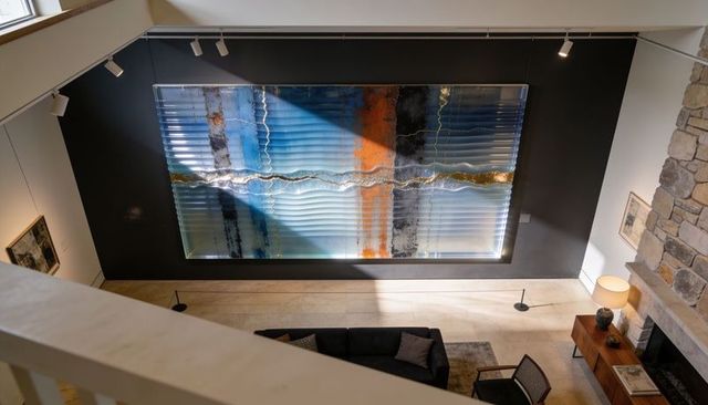 Textured multipanel artwork catching diagonal sunlight over modern mezzanine living room