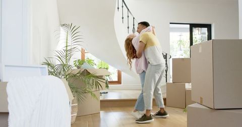 Happy Couple Embracing in New Home Among Moving Boxes