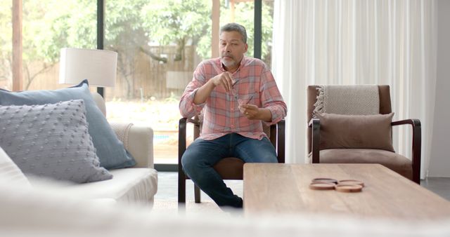 Middle-aged man sitting in living room holding glasses - Download Free Stock Images Pikwizard.com