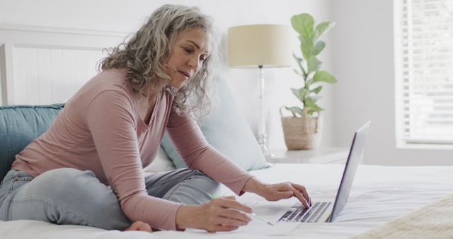 Mature Woman Working on Laptop in Cozy Bedroom Setting - Download Free Stock Images Pikwizard.com