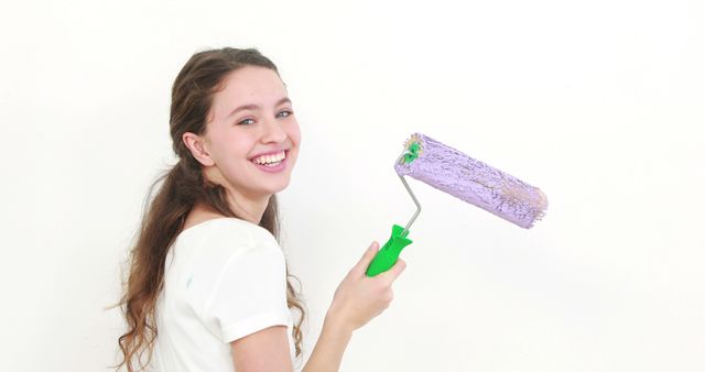 Smiling Woman Painting Wall with Roller and Purple Paint - Download Free Stock Images Pikwizard.com