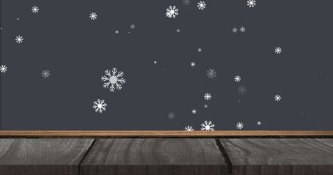 Snowflakes falling on wooden surface with dark background