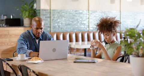 African american coworkers working in cafe with laptop and coffee, casual coworking