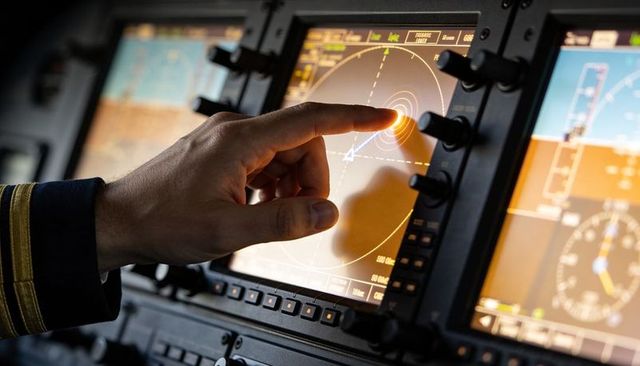 Pilot touching cockpit touchscreen selecting waypoint on navigation display