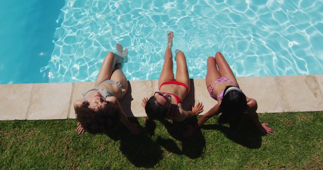 Group of three friends lounging at the edge of a swimming pool on a sunny summer day. Ideal for illustrating scenes of leisure, enjoyment, and vacation. Great for use in summer campaigns, travel brochures, social media posts promoting summer activities, and advertisements for swimwear or vacation spots.