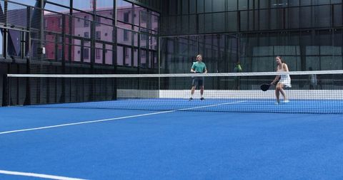 Urban padel match on blue court indoors with players