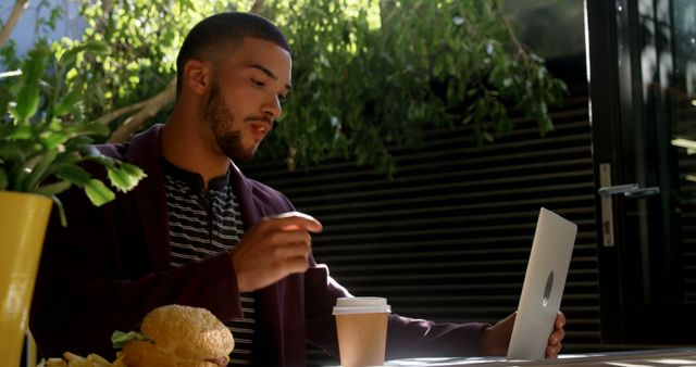 Young Man Working on Laptop in Cafe While Enjoying Lunch - Download Free Stock Images Pikwizard.com