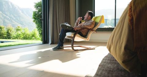 Serene Reflection: Man Enjoys Scenic Mountain View from Modern Lounge
