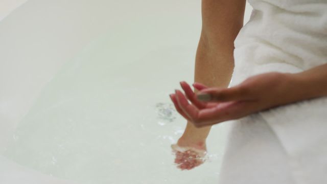 Close-up of person's hands while running water for a bath at home. Ideal for topics on self-care, relaxation, and home lifestyle. Can be used in articles, advertisements or blogs about personal care routines, at-home relaxation techniques, or domestic tranquility.