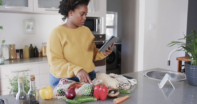 Woman Using Tablet While Unpacking Groceries in Modern Kitchen - Download Free Stock Images Pikwizard.com