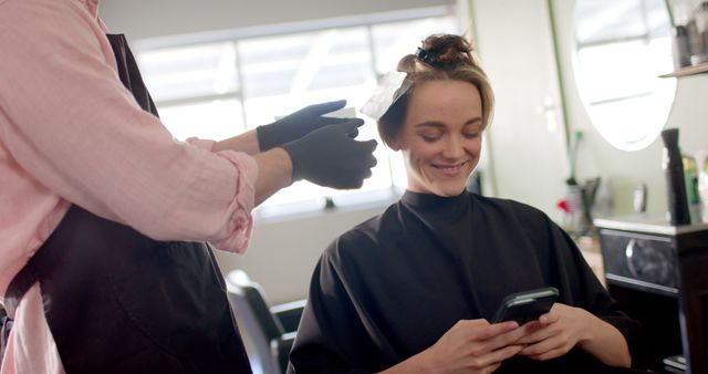 Woman Smiling While Using Phone at Hair Salon - Download Free Stock Images Pikwizard.com