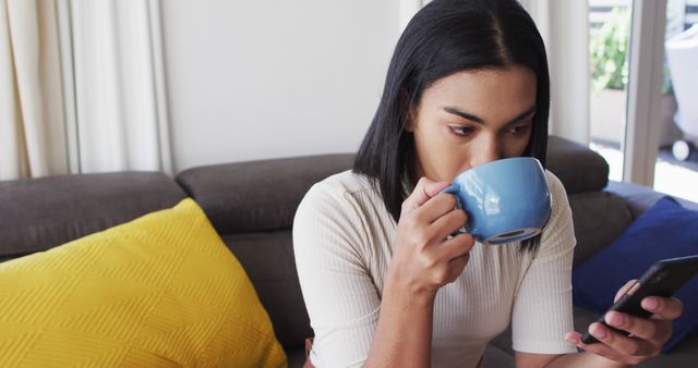 Woman Drinking Coffee and Using Smartphone on Couch in Living Room - Download Free Stock Images Pikwizard.com