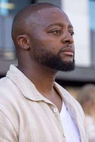 Confident african american man standing in urban plaza wearing casual beige shirt