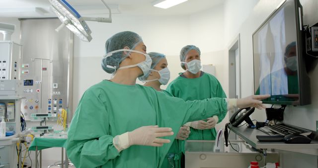 Medical Team in Surgical Attire Consulting Monitors in Operating Room - Download Free Stock Images Pikwizard.com