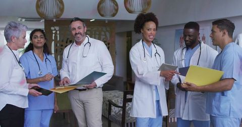 Multicultural medical team collaborating in staff lounge reviewing patient files