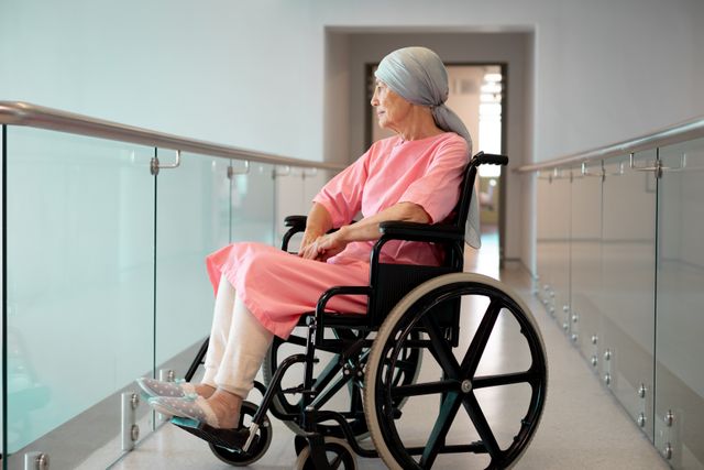 Happy senior caucasian female patient in wheelchair sitting in hospital corridor smiling. Medical services, hospital and healthcare concept.