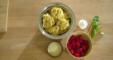 Overhead Pasta Nests with Cherry Tomatoes, Garlic, Basil and Parmesan on Wood Counter