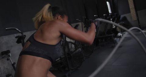 Energetic Woman Training with Battle Ropes in Gym