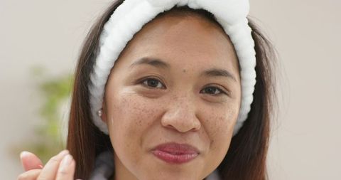 Mid adult asian woman applying cream in self-care routine