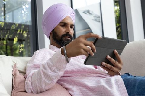 Mid adult indian man relaxing with tablet at home