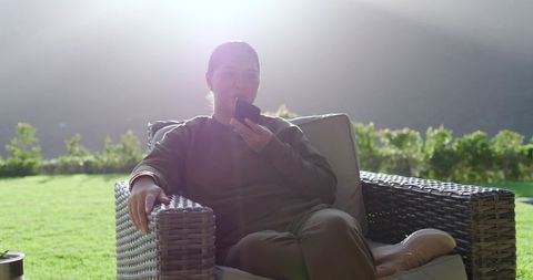 Man relaxing in garden speaking on smartphone sunlit outdoors