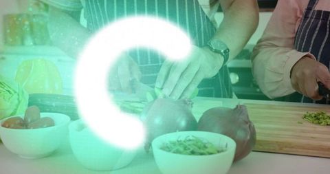 Couple chopping vegetables together in modern kitchen wearing striped aprons