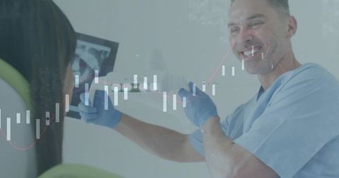Smiling dentist examining patient with intraoral camera and dental x-ray on monitor