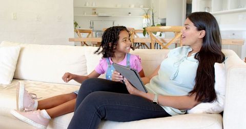 Mother and Daughter Bonding on Couch Using Tablet