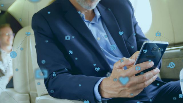 A mature man in a blue suit using his smartphone while seated in a private jet. Floating social media icons represent connectivity and networking in the digital age. Suitable for depicting themes like business travel, social media marketing, tech-savvy professionals, or luxury lifestyle.