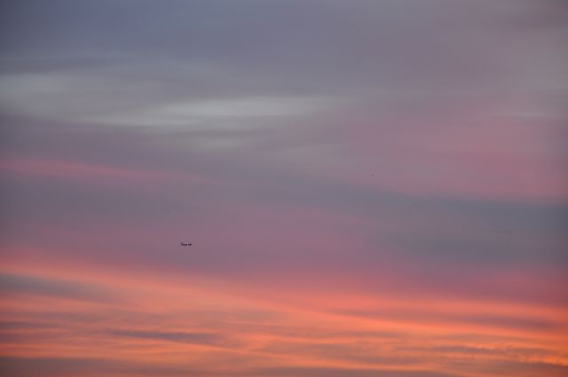 Beautiful scene featuring an airplane flying through a colorful dusk sky, painted with vibrant pastel shades. Ideal for travel agency promotions, aviation industry publications, scenic backgrounds, inspirational posters, and digital wallpapers.