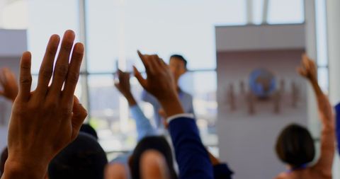 Diverse Audience Raising Hands in Business Seminar Focus