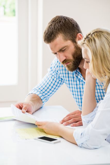 Worried couple checking bills at home