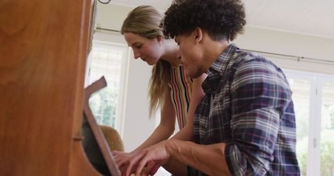 Diverse Couple Joyfully Playing Piano Together at Home