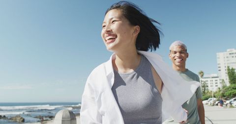 Joyful couple strolling along sunny seaside promenade