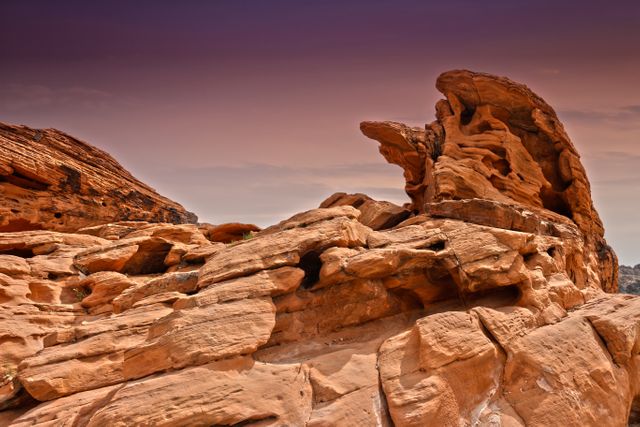 Stunning view of red sandstone rocks in a desert landscape during a beautiful sunset. The formation illustrates natural erosion and geological shapes, making it perfect for themes involving nature, wilderness, and outdoor adventures. Useful for travel advertisements, nature blogs, geological studies, or background art for presentations on natural wonders.