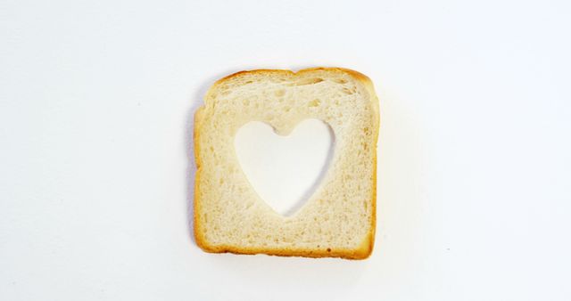 A slice of bread with a heart-shaped hole in the center is presented against a white background, with copy space. Its unique design suggests a concept of love, diet, or creative food presentation.