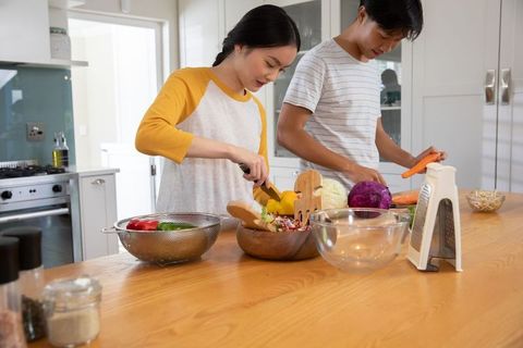 Couple preparing fresh vegetable salad in modern kitchen