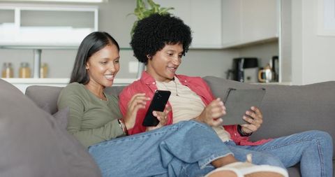 Couple Relaxing in Modern Living Room with Tablet and Smartphone