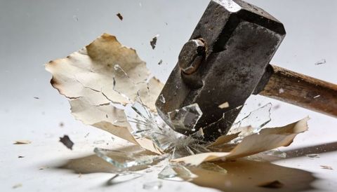 Sledgehammer smashing shattered glass and torn paper close-up of impact debris