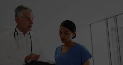 Doctor and Nurse Collaborating Over Tablet in Bright Clinic Corridor for Patient Care