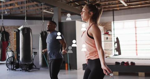 Diverse athletes skipping rope in modern gym with digital overlay