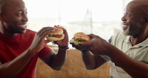 Joyful Shared Moment with Burgers Indoors - Download Free Stock Images Pikwizard.com