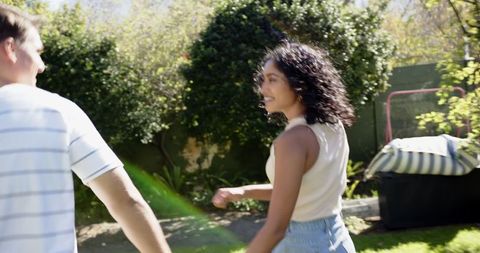 Romantic Couple Strolling Hand in Hand in Sunlit Backyard