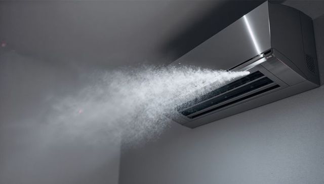 Modern air conditioner emitting cool mist in minimalist interior
