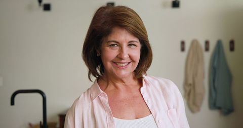 Senior Woman Smiling in Kitchen by Stylish Black Faucet