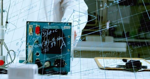 Scientist formulating advanced equations behind glass board