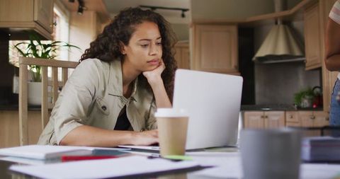 Focused Woman Working on Laptop from Home Kitchen